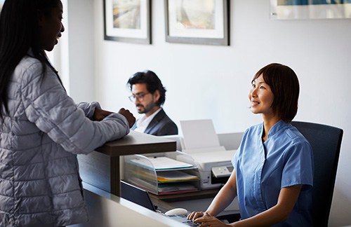 front desk dental team member helping a patient