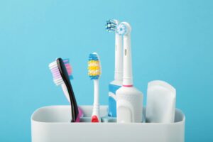 An assortment of toothbrushes in a container with a pale blue background